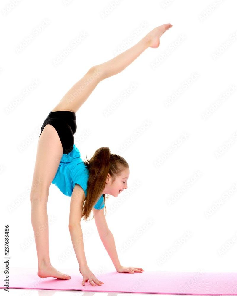 The little gymnast perform an acrobatic element on the floor. The little gymnast perform an acrobatic element on the floor.