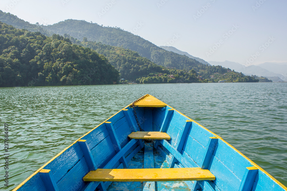 wooden blue yellow boat on the lake against the background of green mountains