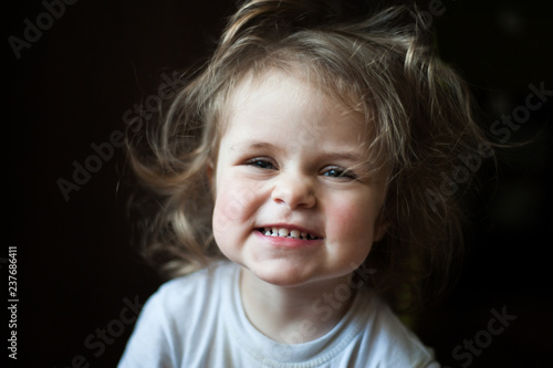 Closeup portrait of a child. Smiles and shows teeth. Shaggy girl. Emotional concept