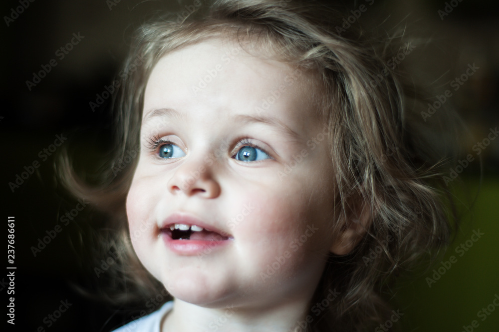 Closeup portrait of a child. Happily and in surprise looks to the side. Shaggy girl. Emotional concept Closeup portrait of a child. Happily and in surprise looks to the side. Shaggy girl. Emotional concept