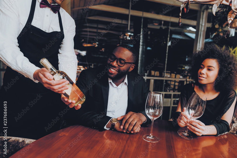Obraz premium African Couple Offerring Bottle Wine in Restaurant