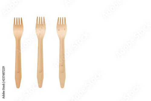 Three wooden forks on a white isolate background in the left part ob the frame. Plugs from natural materials. Safe disposable utensils to preserve the environment. Flat lay. Copy space.