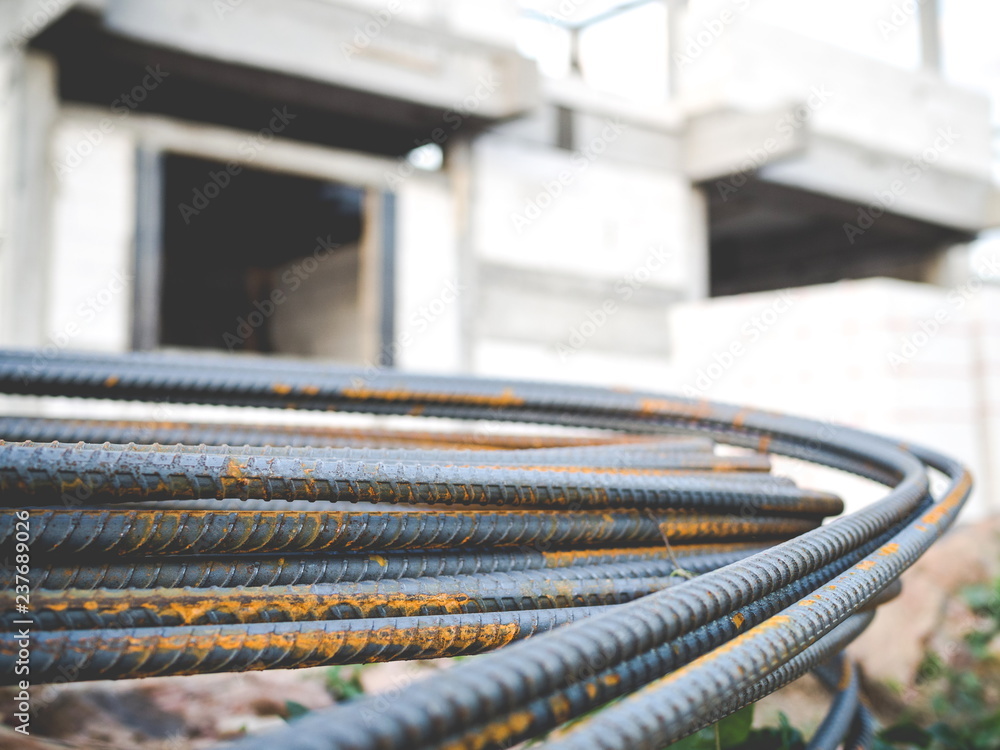 Stack of steel rebar for reinforcement concrete with house under construction background Stack of steel rebar for reinforcement concrete with house under construction background