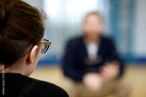 Over the shoulder profile of a girl in glasses getting counselling over mental health issues.