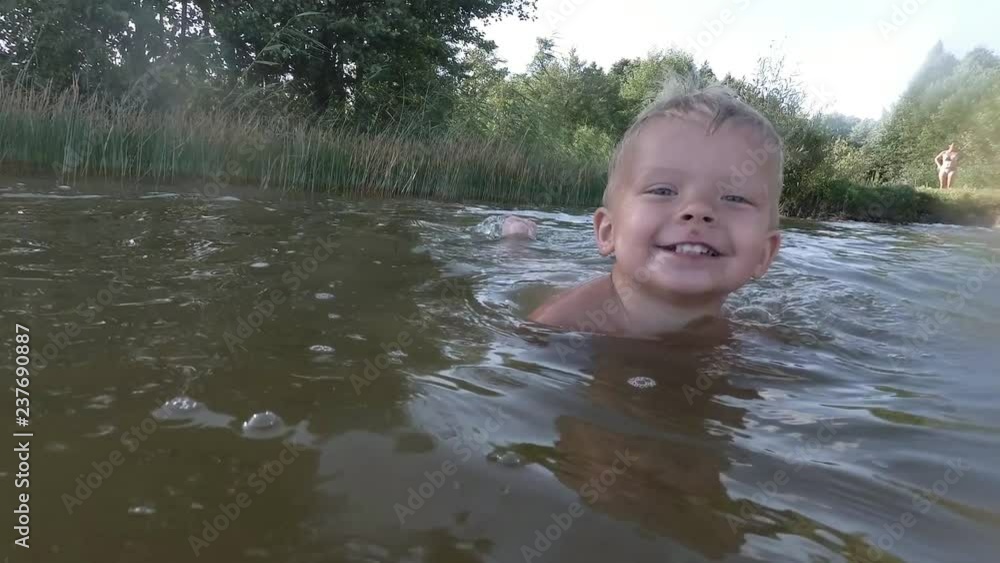 Happy little boy making splashes in water. Child having fun in the lake. Happy little boy making splashes in water. Child having fun in the lake.