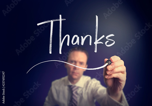 A businessman writing a Thanksconcept with a white pen on a clear screen.