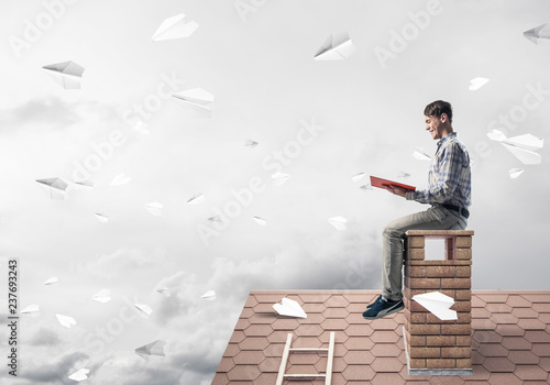 Handsome student guy reading book and paper planes flying in air
