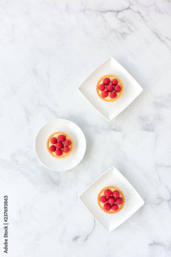 Tartlets filled with Raspberries and Lemon Cream on White Marble Tartlets filled with Raspberries and Lemon Cream on White Marble