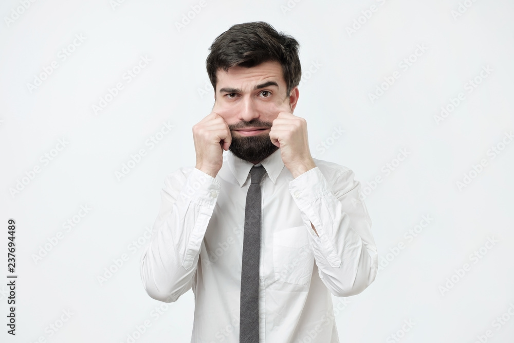 Problems with skin and wrinkles. Handsome spanish man in white shirt stretching his skin on face. Extra skin on the face after losing weight Problems with skin and wrinkles. Handsome spanish man in white shirt stretching his skin on face. Extra skin on the face after losing weight