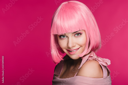 beautiful stylish young woman in pink wig biting lip, isolated on pink