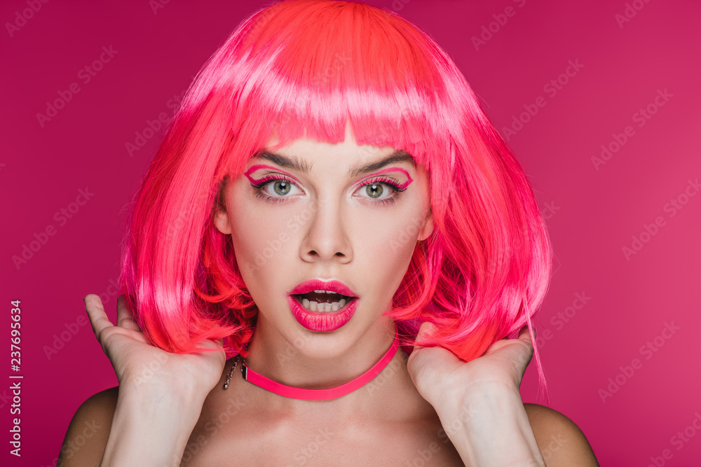 shocked fashionable girl posing in neon pink wig, isolated on pink
