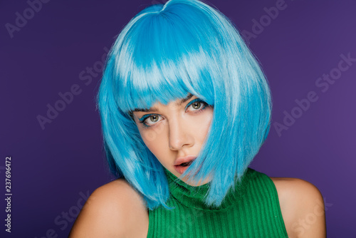 beautiful stylish girl posing in blue wig, isolated on purple