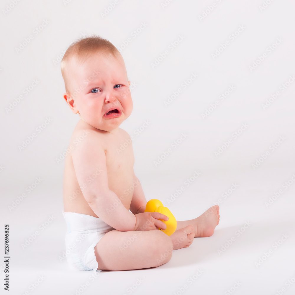 Crying baby in diaper sitting on the ground Crying baby in diaper sitting on the ground