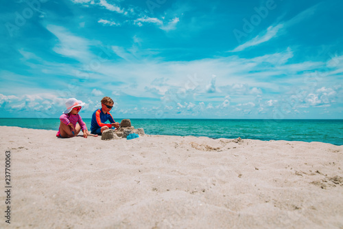 little boy and girl play with sand on beach