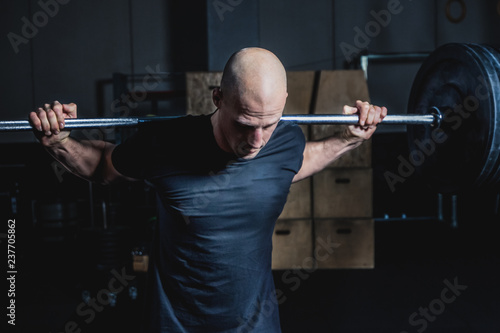 Athletic Muscular Man Holding Barbell On Your Shoulders In Gym. Dramatic Color Grading.