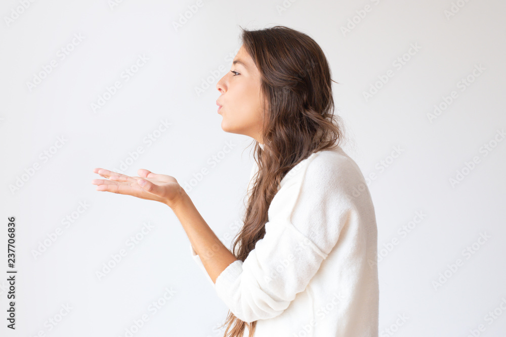 Beautiful Hispanic girl blowing air kiss from hands. Profile portrait of stylish young woman. Isolated on white. Love concept Beautiful Hispanic girl blowing air kiss from hands. Profile portrait of stylish young woman. Isolated on white. Love concept
