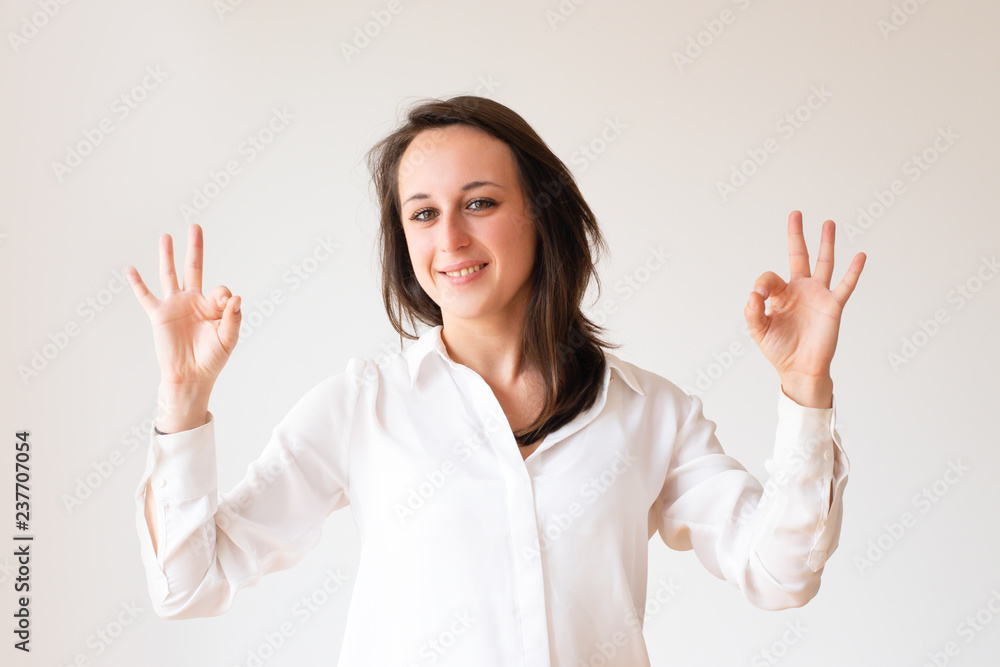Cheerful young businesswoman showing ok signs. Beautiful student gesturing okey symbol. Isolated on white. Positivity concept Cheerful young businesswoman showing ok signs. Beautiful student gesturing okey symbol. Isolated on white. Positivity concept
