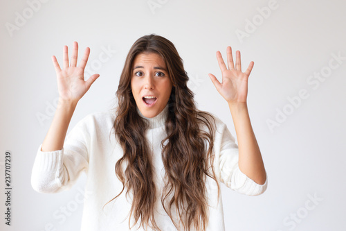 Frightened Hispanic girl shouting with hands up. Attractive scared woman with long hair looking at camera. Isolated on white. Stress concept