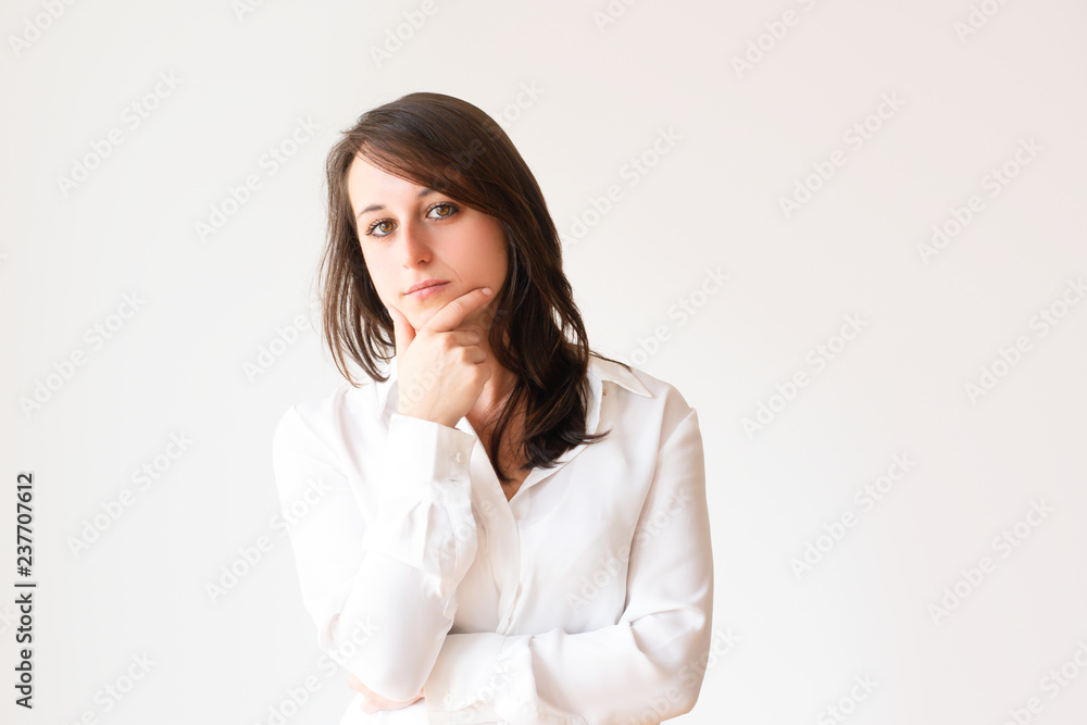 Pensive beautiful student holding chin and looking at camera. Elegant thoughtful female manager in white blouse. Isolated on white. Thinking concept Pensive beautiful student holding chin and looking at camera. Elegant thoughtful female manager in white blouse. Isolated on white. Thinking concept