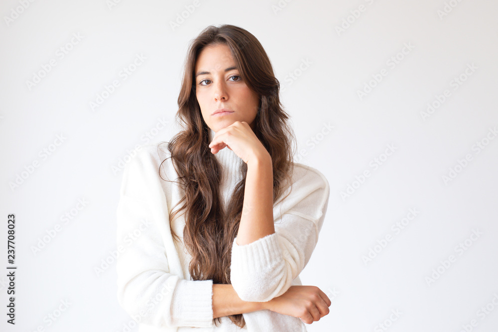 Thoughtful Latin woman holding chin and looking at camera. Beautiful pensive Hispanic girl in white sweater. Isolated on white. Thinking concept Thoughtful Latin woman holding chin and looking at camera. Beautiful pensive Hispanic girl in white sweater. Isolated on white. Thinking concept