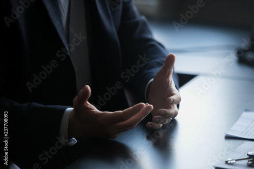 Business meeting. Confident businessman sitting at the table at the meeting. Close-up view of the hands of successful businessmen. Businessman showing hand gestures