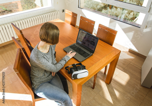 Young woman wearing virtual reality glasses and a laptop in an office. VR glasses, entertainment, technology