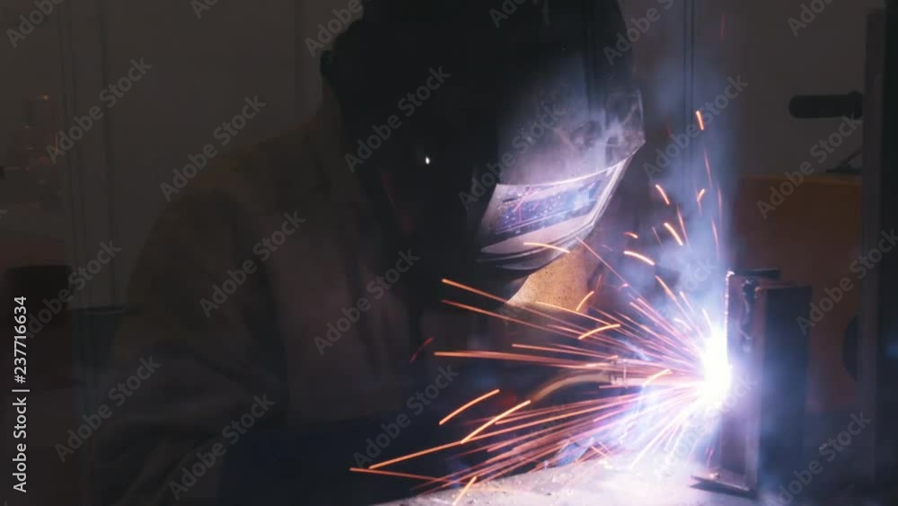 Welding process. A welder in helmet doing his job in the dark. Smoke and sparks Welding process. A welder in helmet doing his job in the dark. Smoke and sparks
