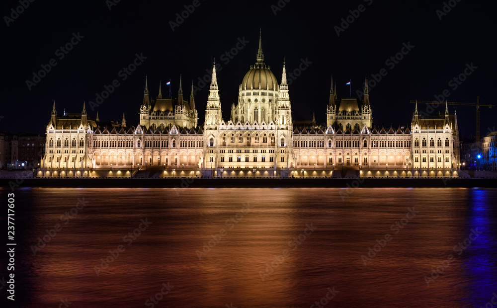 Hungarian Parliament building, in Budapest, at night.  The building is lit up, and the Danube is flowing smoothly in front of it.