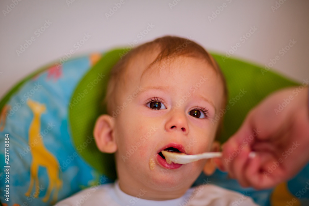 Mom is feeding her baby in the highchair at home.. Mom is feeding her baby in the highchair at home..