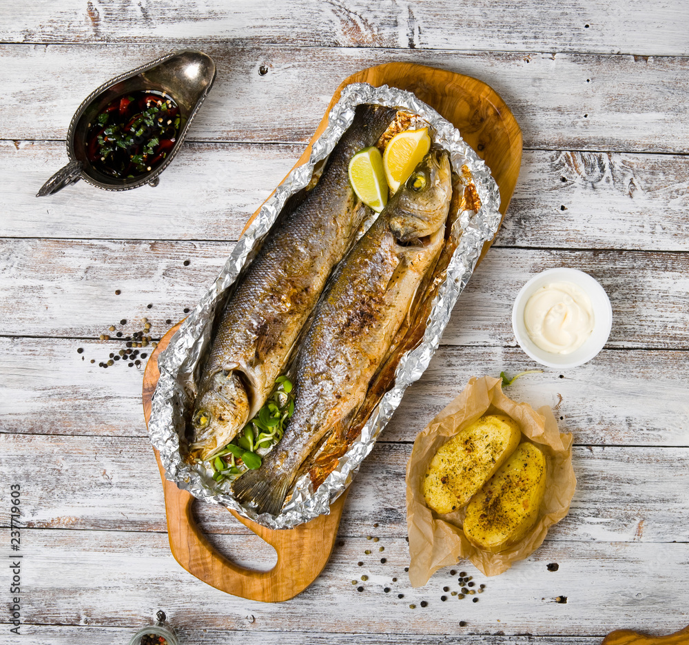 Fresh baked fish sea bass (Dicentrarchus labrax) on a light wooden background
