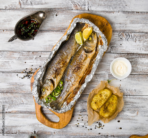 Fresh baked fish sea bass (Dicentrarchus labrax) on a light wooden background photo