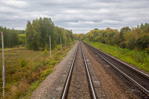 Railway. View from the window of the last train car or from the cab. Russian autumn landscape. Railway rails and sleepers.