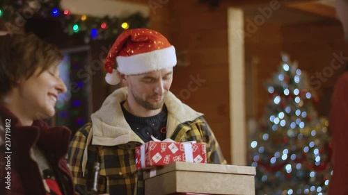Family couple gives Xmas present and bottle of wine to their friend