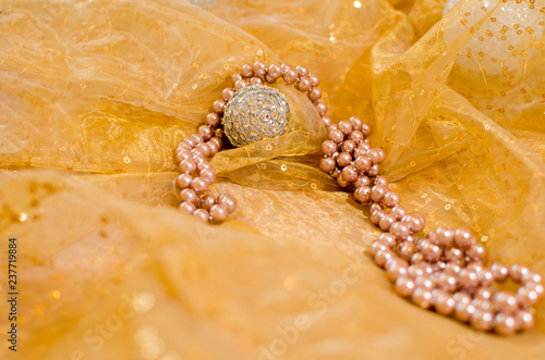Glamour carnival background with a pearl necklace and gleaming ornaments in a pastel warm color