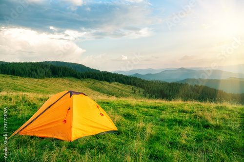 Orange tourist tent in the mountains under bright sun