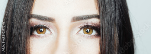 Eyes. Beautiful brown hazel eyes of young female surrounded by her black hair. Sincere look from young woman. Simple fresh concept of female eyes. Nude make up for daily walk. Fresh clean skin