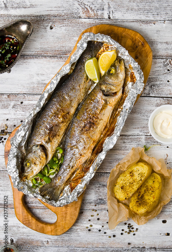 Fresh baked fish sea bass (Dicentrarchus labrax) on a light wooden background