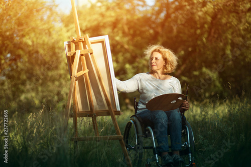 Fotografie Woman in wheelchair drawing on easel outside