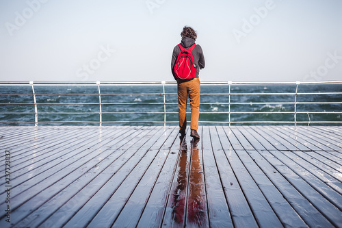 Mid adult man looking out from pier to sea, rear view, Odessa, Odeska Oblast, Ukraine photo