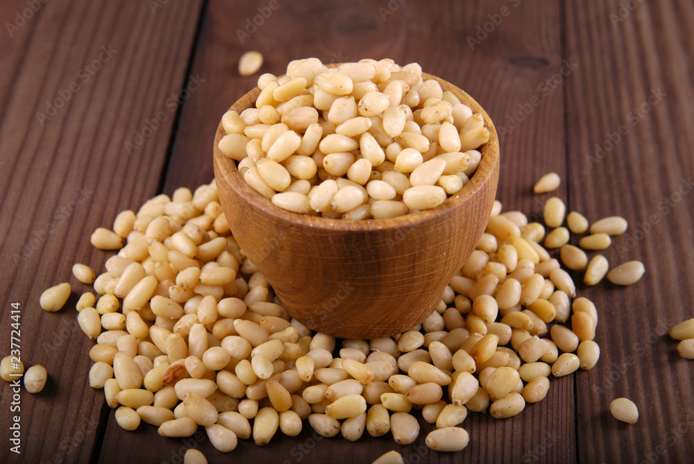 Kernels of pine nuts in a bowl on a dark wooden background.