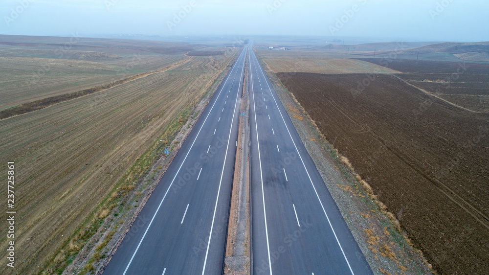 Aerial view on  speed road, partly covered by fog. Vertical view on rural countryside in autumn, foggy morning. Misty empty road.