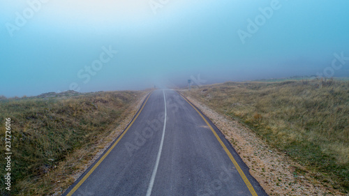 Aerial view on speed road, partly covered by fog. Vertical view on rural countryside in autumn, foggy morning. Misty empty road.