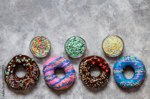 homemade doughnuts with colored frosting and different sprinkles on a gray background