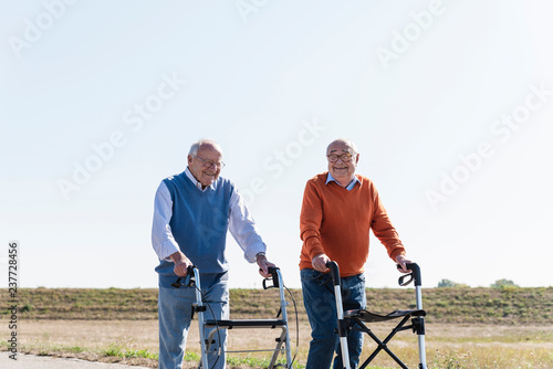 Two old friends walking on a country road, using wheeled walkers photo