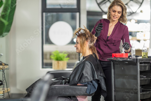 Hairdresser colouring customer's hair in salon