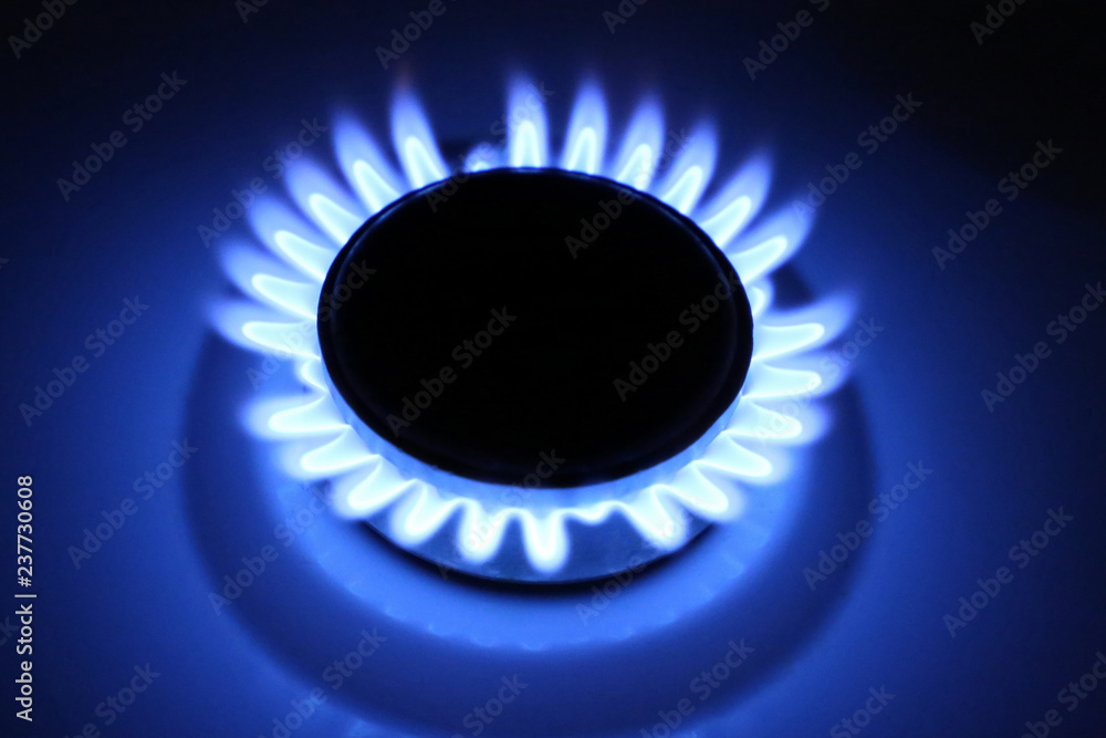Burning gas on stove burner. Blue flame in darkness, household gas