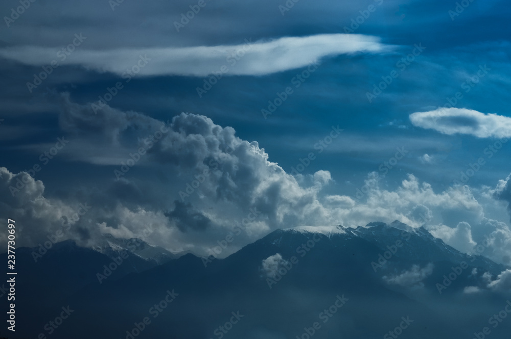 Dramatic landscape of peak mountains with clouds and sunlight.