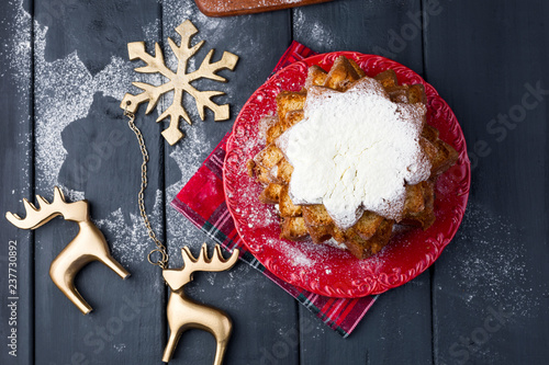 Italian Christmas cupcake with powdered sugar. Traditional festive pastries in the form of stars and decor on a dark wooden background. Top view. Free space to copy text.
