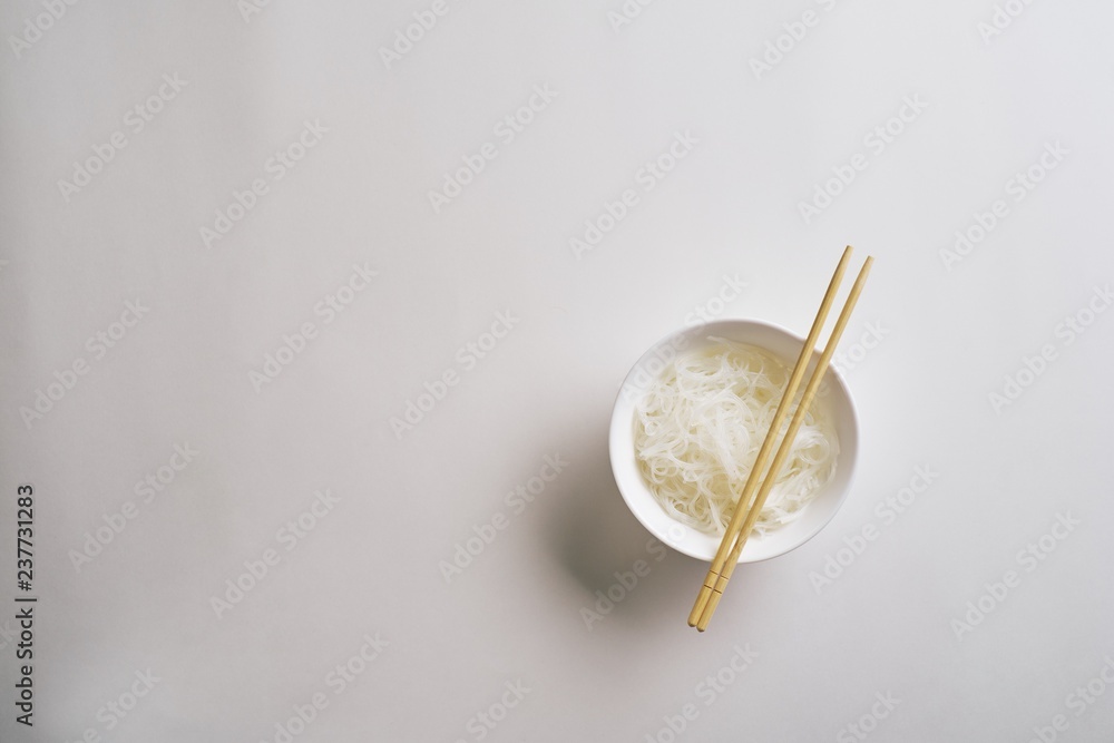Rice noodles in a plate with chopsticks. Boiled rice noodles in a plate on a white background. Top view Rice noodles in a plate with chopsticks. Boiled rice noodles in a plate on a white background. Top view