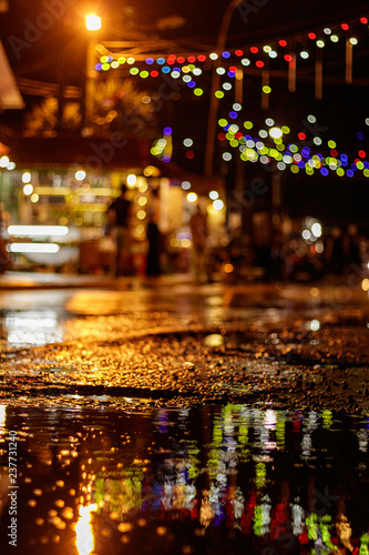 Wet street at night with bright colorful decorations